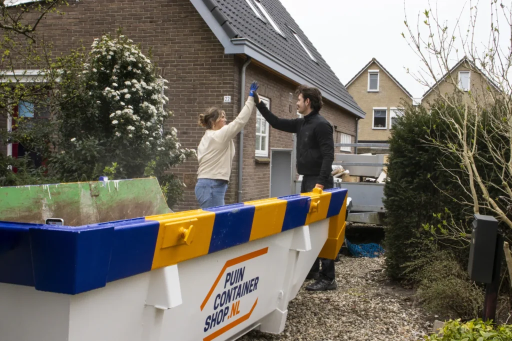 Twee mensen geven elkaar een high five naast een afzetcontainer van Puincontainershop.nl